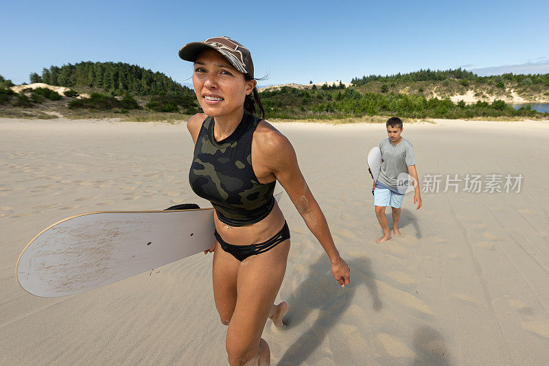 活跃的妈妈和十几岁的儿子玩沙滩冲浪