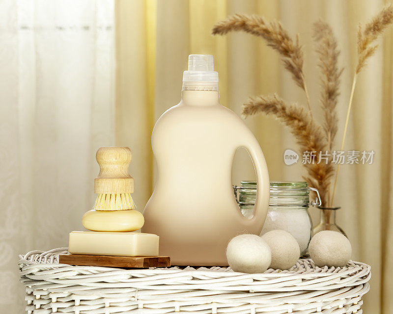 将一瓶洗洁精与肥皂、刷子和洗衣球放在洗衣篮上