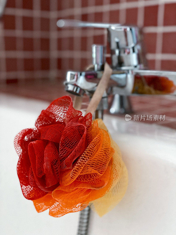 浴缸龙头上挂着红、橙、黄三色的海绵