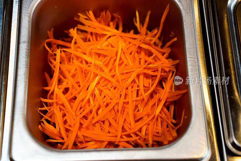 图为胡萝卜切成小片放在托盘上，作为即食沙拉的原料。