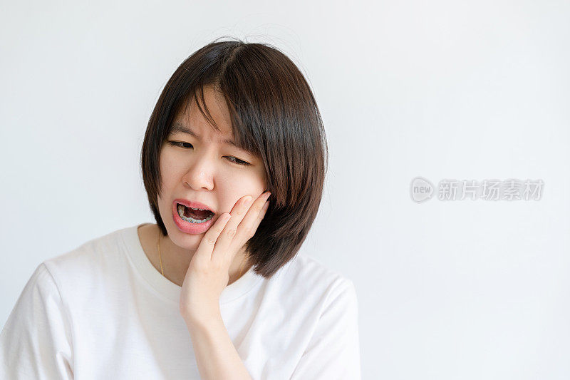 一位女士因为牙痛，摸了摸自己的脸颊。