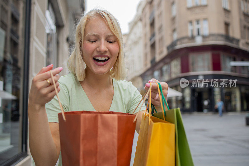一个快乐的女人的肖像享受购物在城市