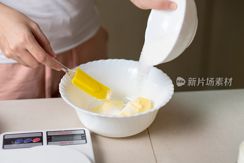 一名妇女在家里的厨房里一边做饼干一边搅拌配料