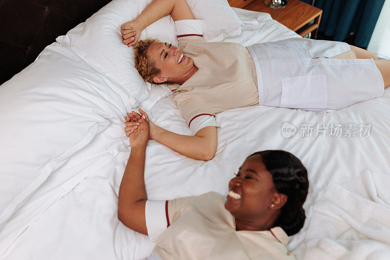 多种族的女佣们躺在床上一起开怀大笑