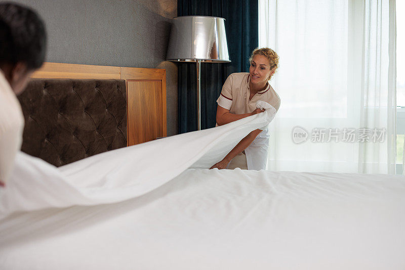 白种人和非裔美国女佣一起叠干净的床单