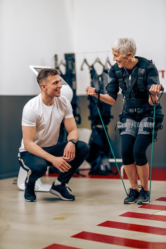 老年妇女在健身房和教练一起做EMS锻炼