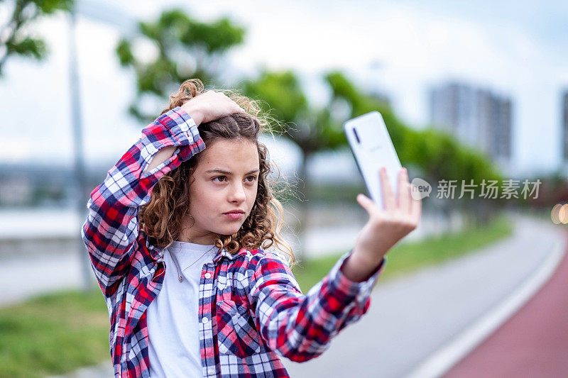 漂亮的少女在用智能手机自拍。