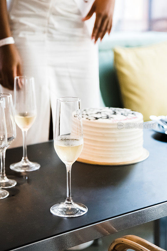 未婚女子。桌子上放着主题蛋糕和香槟酒杯，背景是一个模糊的人。垂直的照片。近距离