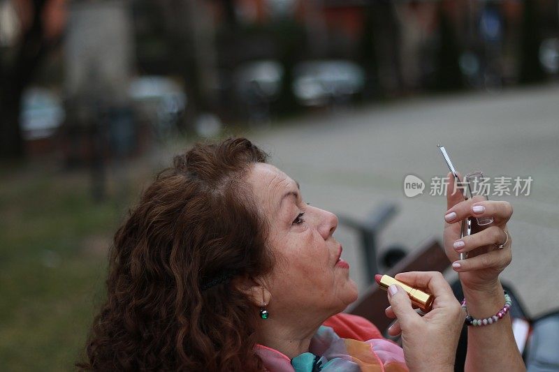 老年妇女手里拿着镜子在补妆