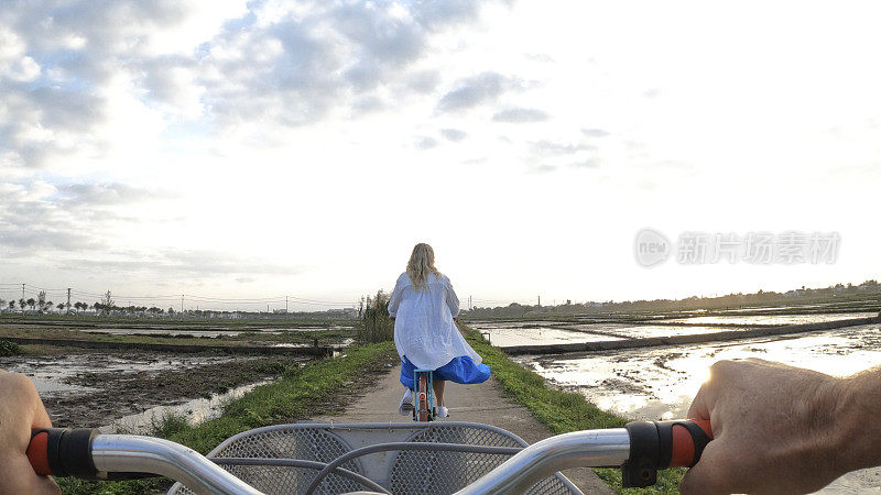 成熟的夫妇骑着自行车穿过稻田