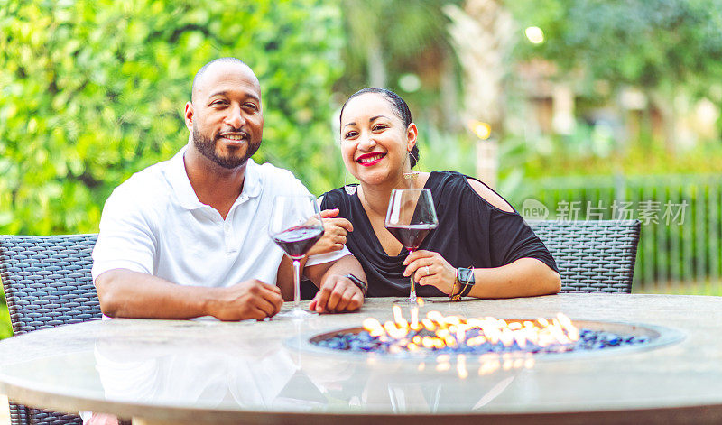 一对幸福相爱的非裔美国夫妇在户外露台上喝着葡萄酒