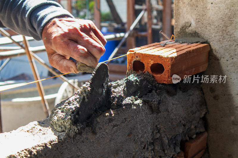 在建筑房屋施工中，抹灰后工人的手在砌砖