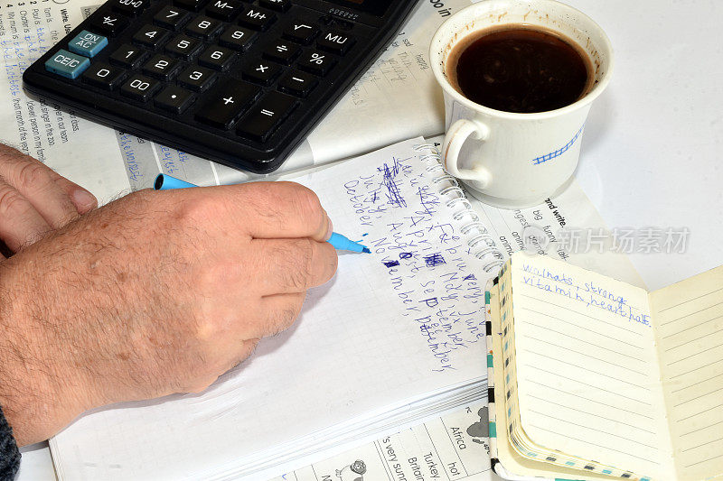 一个男人用钢笔在记事本上写字。