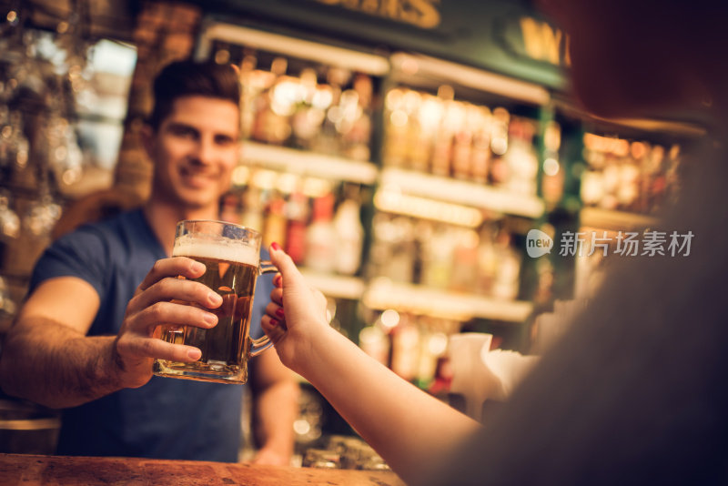 特写的酒保给顾客啤酒在酒吧。