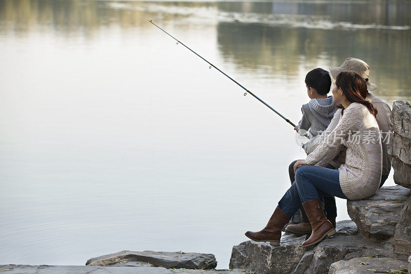 一家人在湖边的岩石上钓鱼