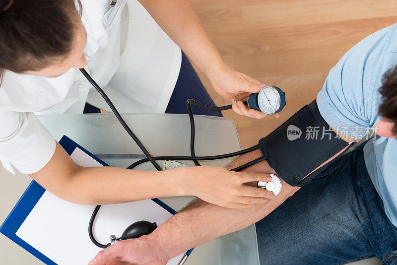医生为男性病人测量血压
