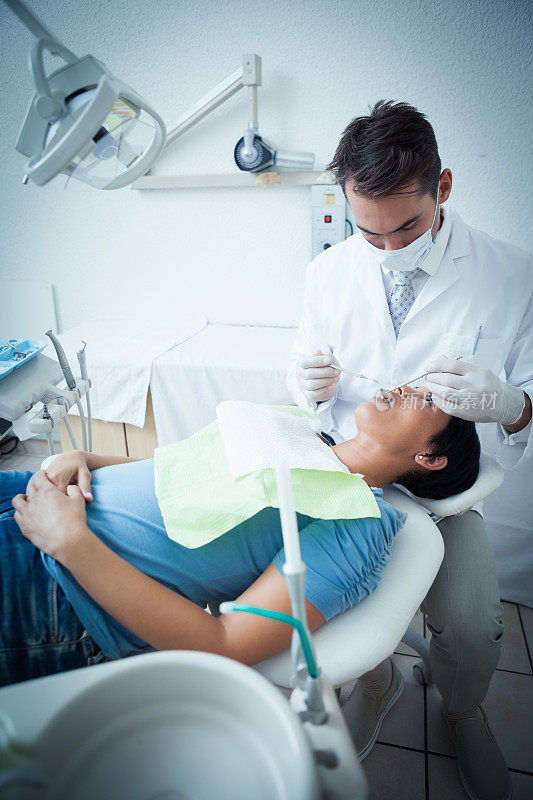 男牙医正在检查女士的牙齿
