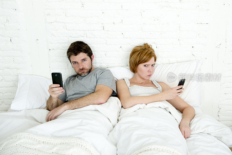 夫妻在床上玩手机，忽略对方