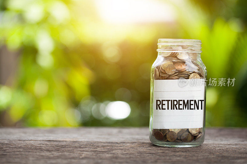退休字与硬币在玻璃罐中，储蓄和金融投资的概念。