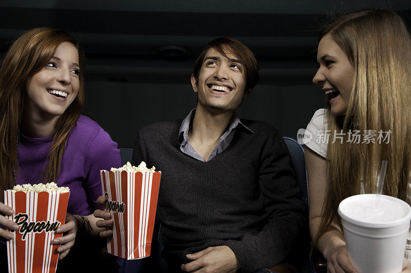 朋友们在电影院吃着爆米花喝着饮料开怀大笑