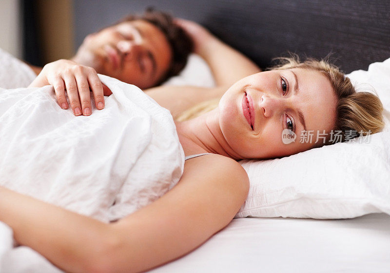 美丽的年轻女子和她的丈夫躺在床上