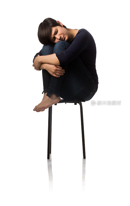 十几岁的女孩坐在椅子上，抱着膝盖