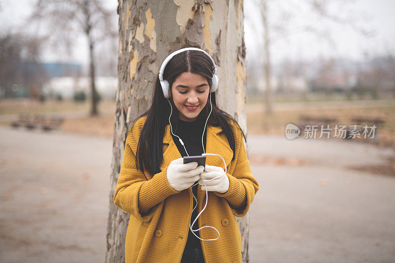 一个女人在当地的公园里戴着耳机听音乐