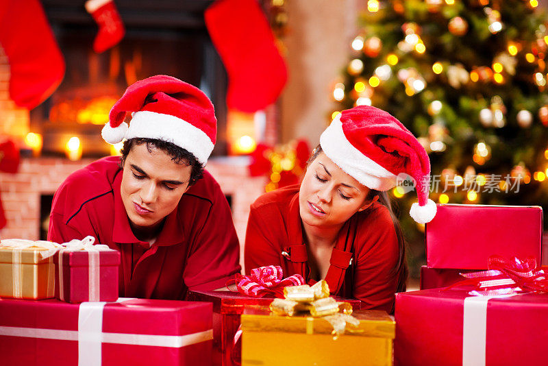 一对无聊的恋人躺在一堆圣诞礼物中间。
