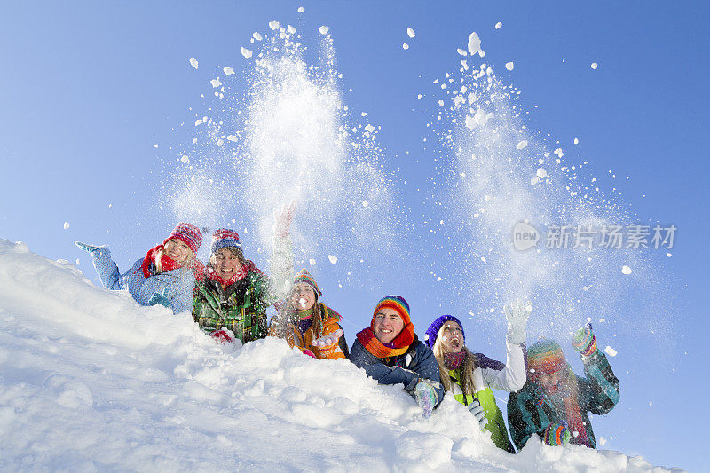 一群快乐的人躺在山上玩雪