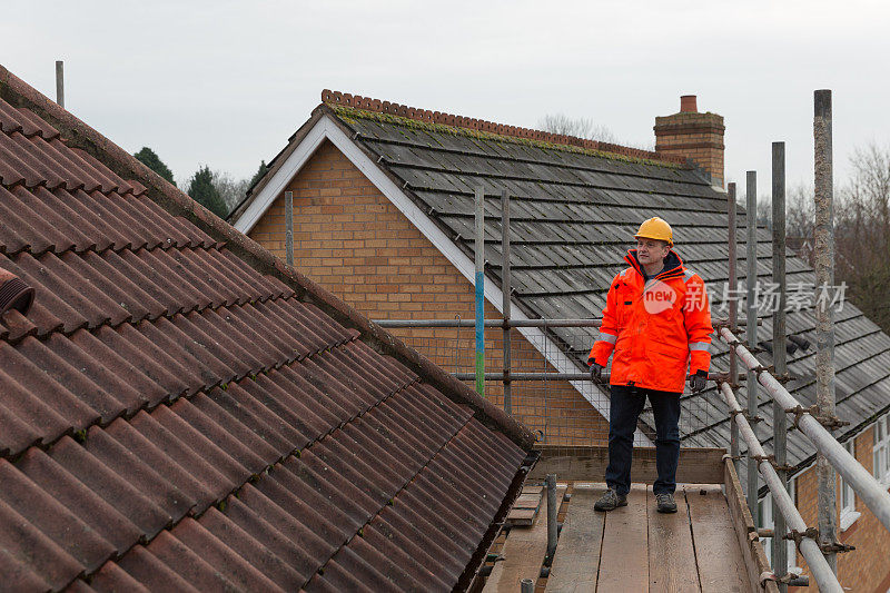工业男建筑工在建筑工地修理屋顶瓦