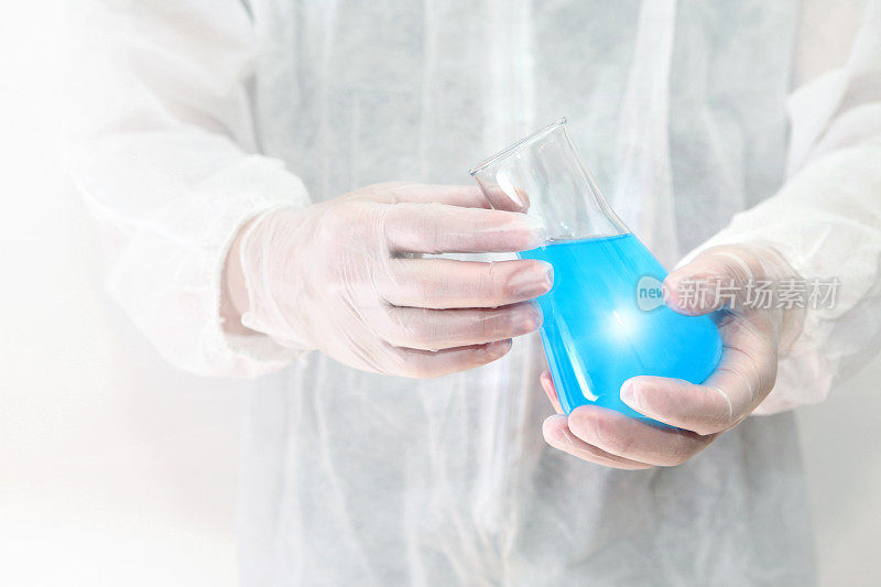 科学实验，生物学家拿着装有蓝色液体的化学玻璃烧瓶