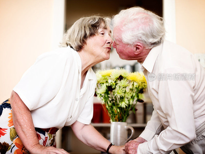爱情伴侣:一对老年情侣倾身亲吻
