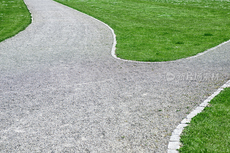 路口砾石步道穿过公园与绿色草地