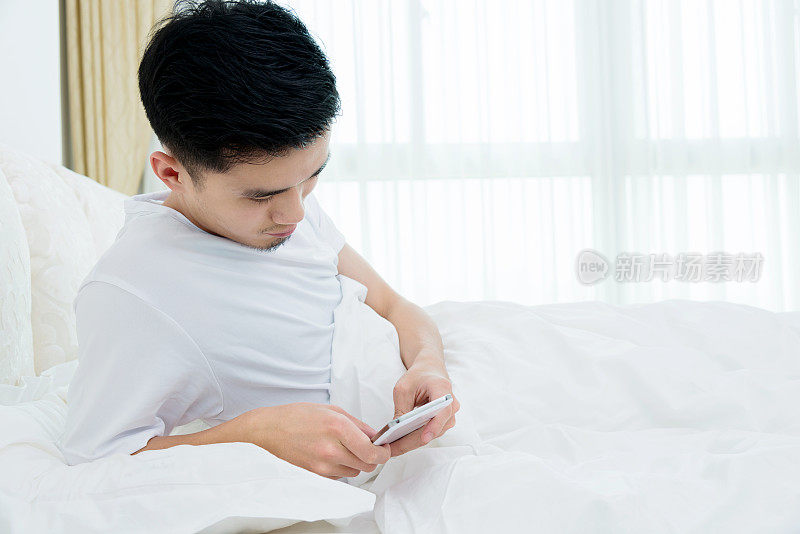 年轻人在床上使用智能手机