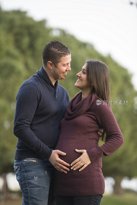 一名男子在公园拥抱怀孕的妻子