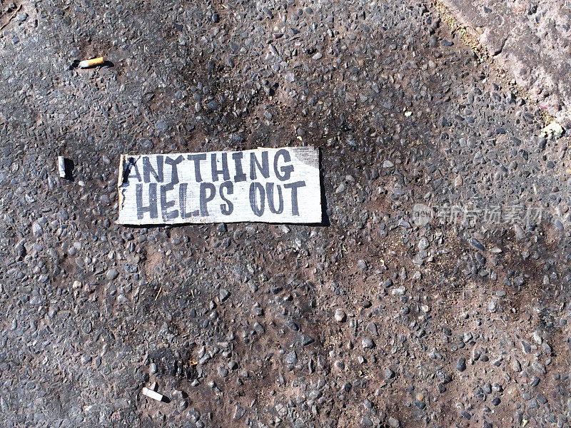 在柏油路和烟头上写着“任何帮助”的标志