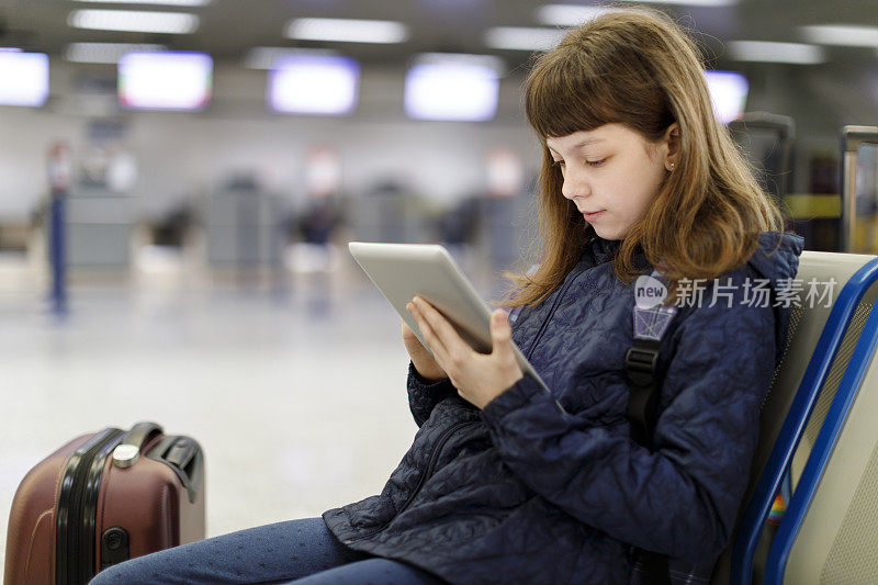 美丽的年轻女孩在机场用她的平板电脑