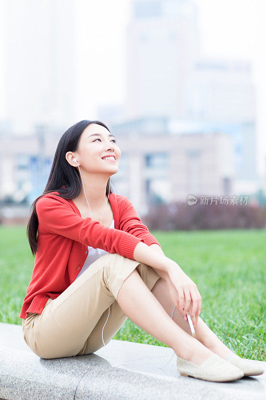 年轻女孩用智能手机的耳机听音乐