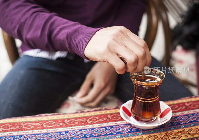 搅拌一杯传统土耳其茶的男人