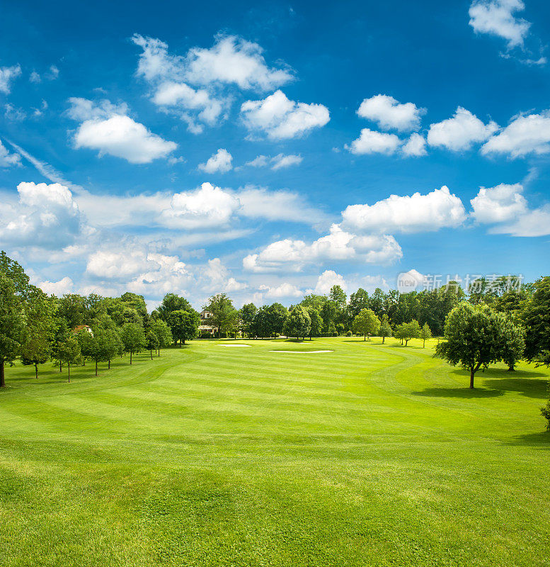 绿色的高尔夫球场和蓝色的多云的天空