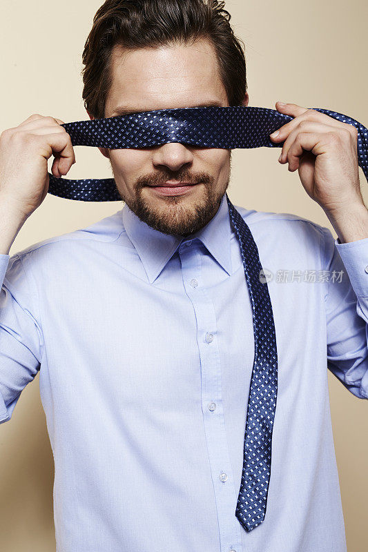 男人用领带遮住眼睛，工作室