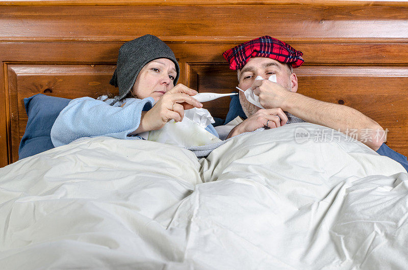 女人和男人躺在床上，嘴里含着温度计，还有一盒纸巾