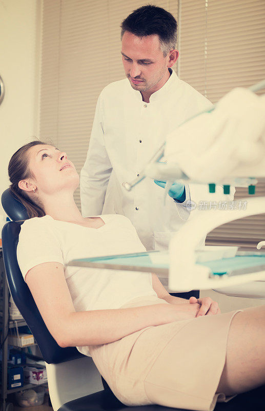 牙医要治疗坐在牙科椅上的女病人