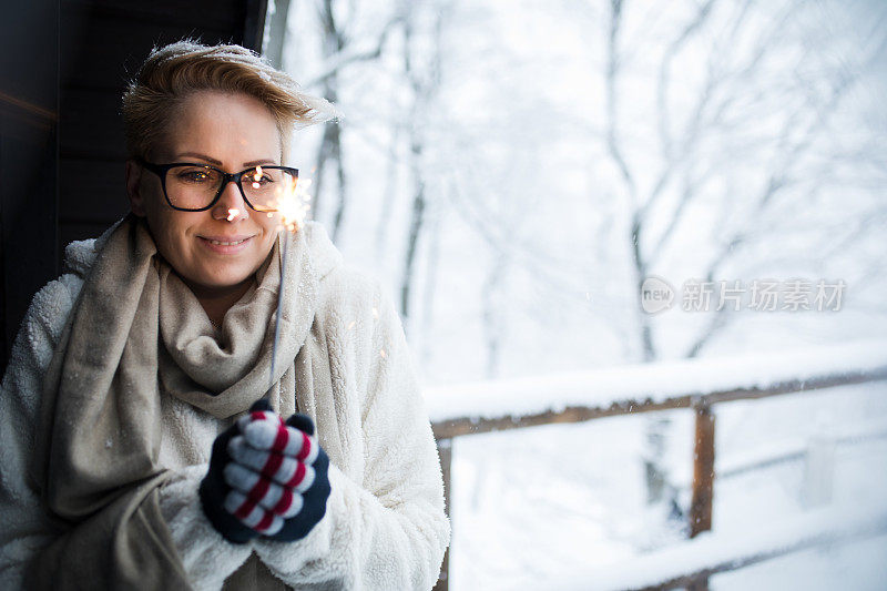 在白雪覆盖的冬天的森林里，一个女人手里拿着一个明亮的圣诞火花