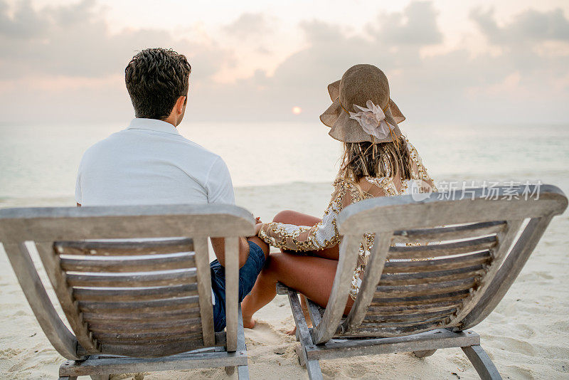 一对成年夫妇在沙滩上的躺椅上休息
