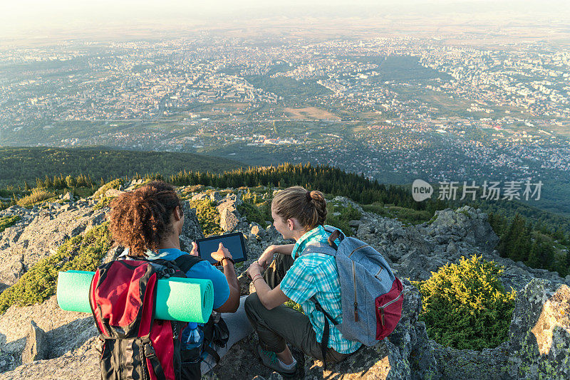 异族情侣一边在山顶上放松，一边在平板电脑上浏览