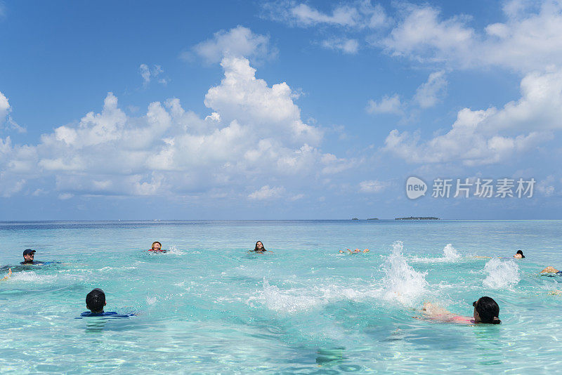 美丽的年轻人，中年和老年人有乐趣在浅水在沙岛海滩在四月，马尔代夫