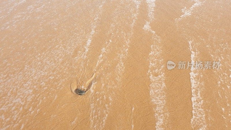 海水中的卵石在沙滩上激起泡沫