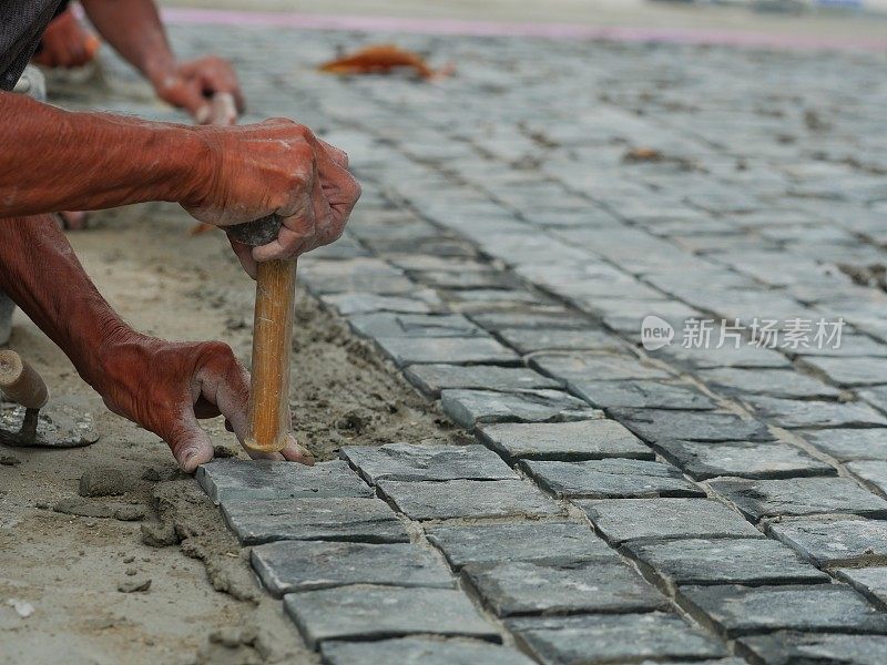 这是泥瓦匠用石块制作人行道的手