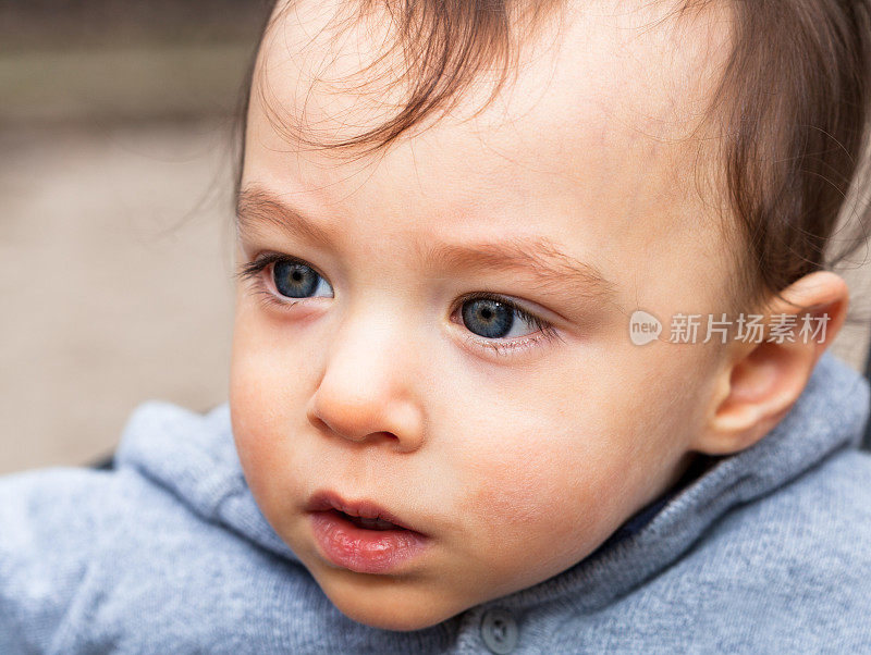 18个月大的蓝眼睛男婴在室外看着别处